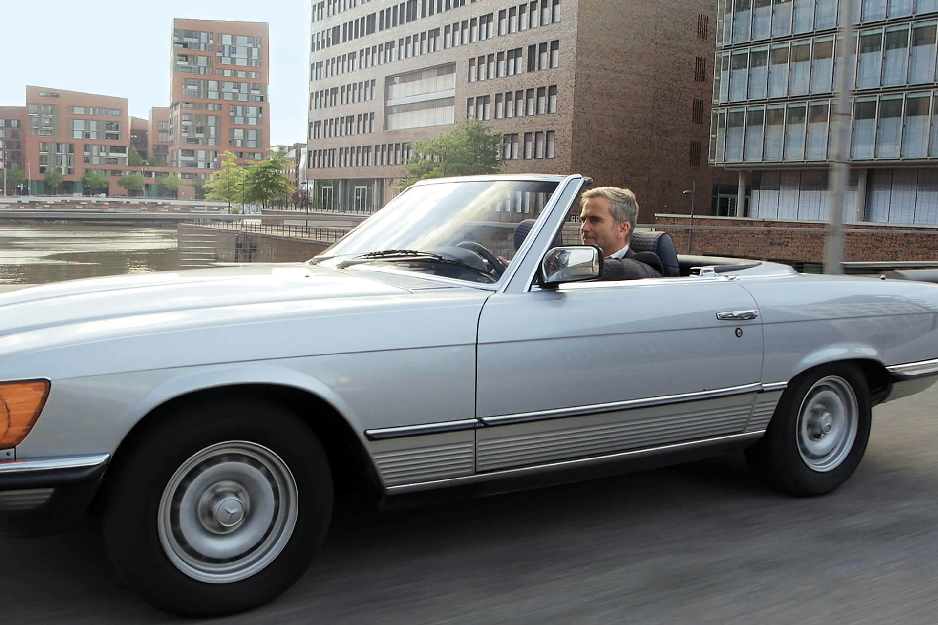 Mann genießt eine Fahrt in einem Cabriolet durch die Stadt